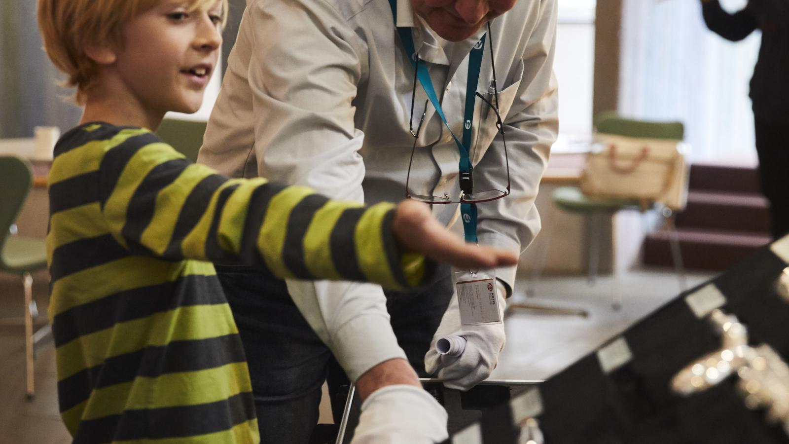 Blick auf einen Jungen, der mit Begeisterung einem Erwachsenen eine Auswahl an Querflöten zeigt