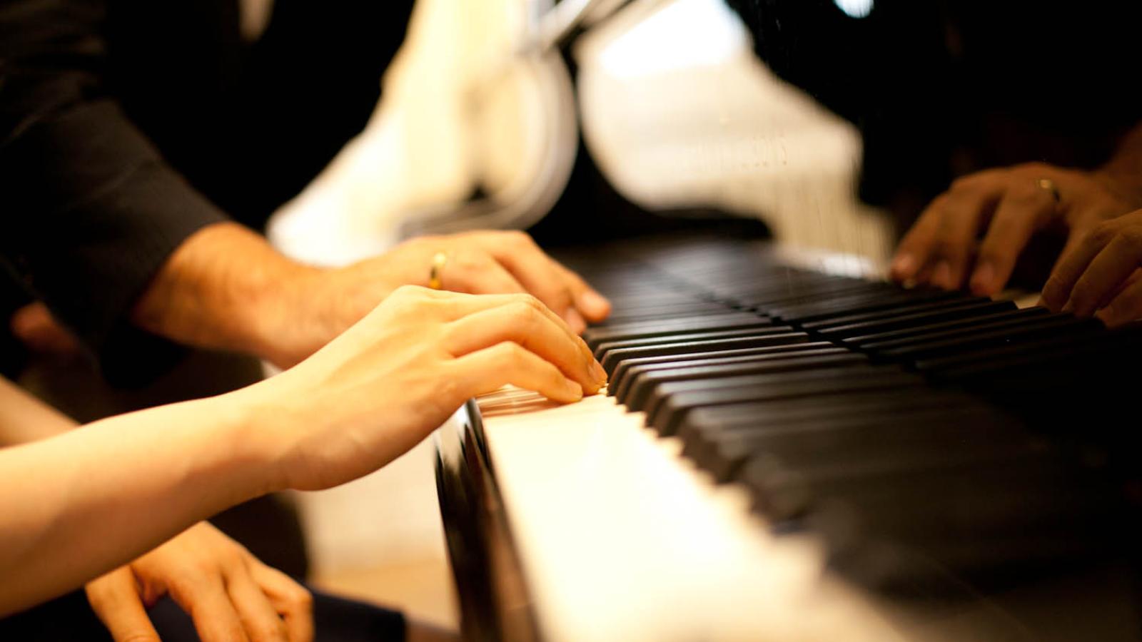 Blick auf Hände, die auf einer Klaviertastatur spielen
