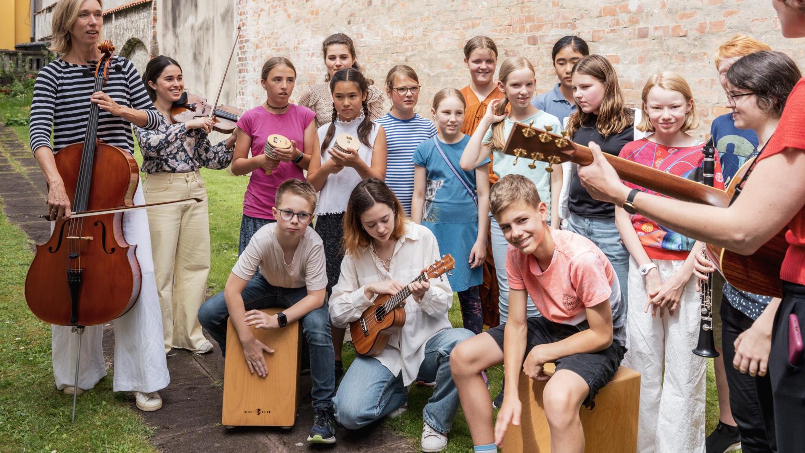 Eine Gruppe Kinder und Jugendlicher machen zusammen Musik und spielen verschiedene Instrumente
