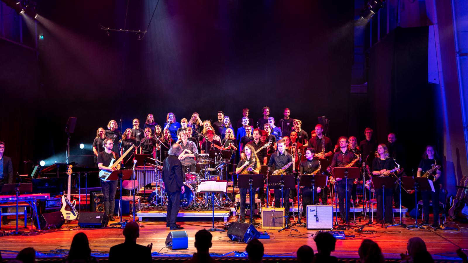 Blick auf die Bühne des Großen Saals der MHL mit einer Vielzahl an Studierenden, die eine Popwerkstatt aufführen 