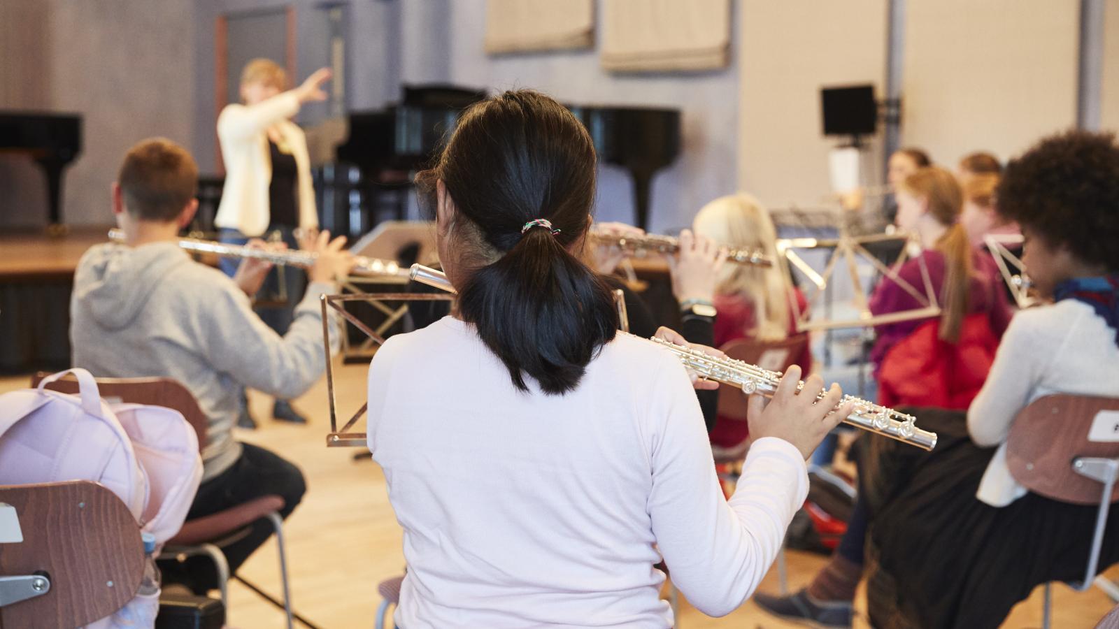 Blick auf musizierende Kinder und Jungendliche, die im Flötenspiel unterrichtet werden