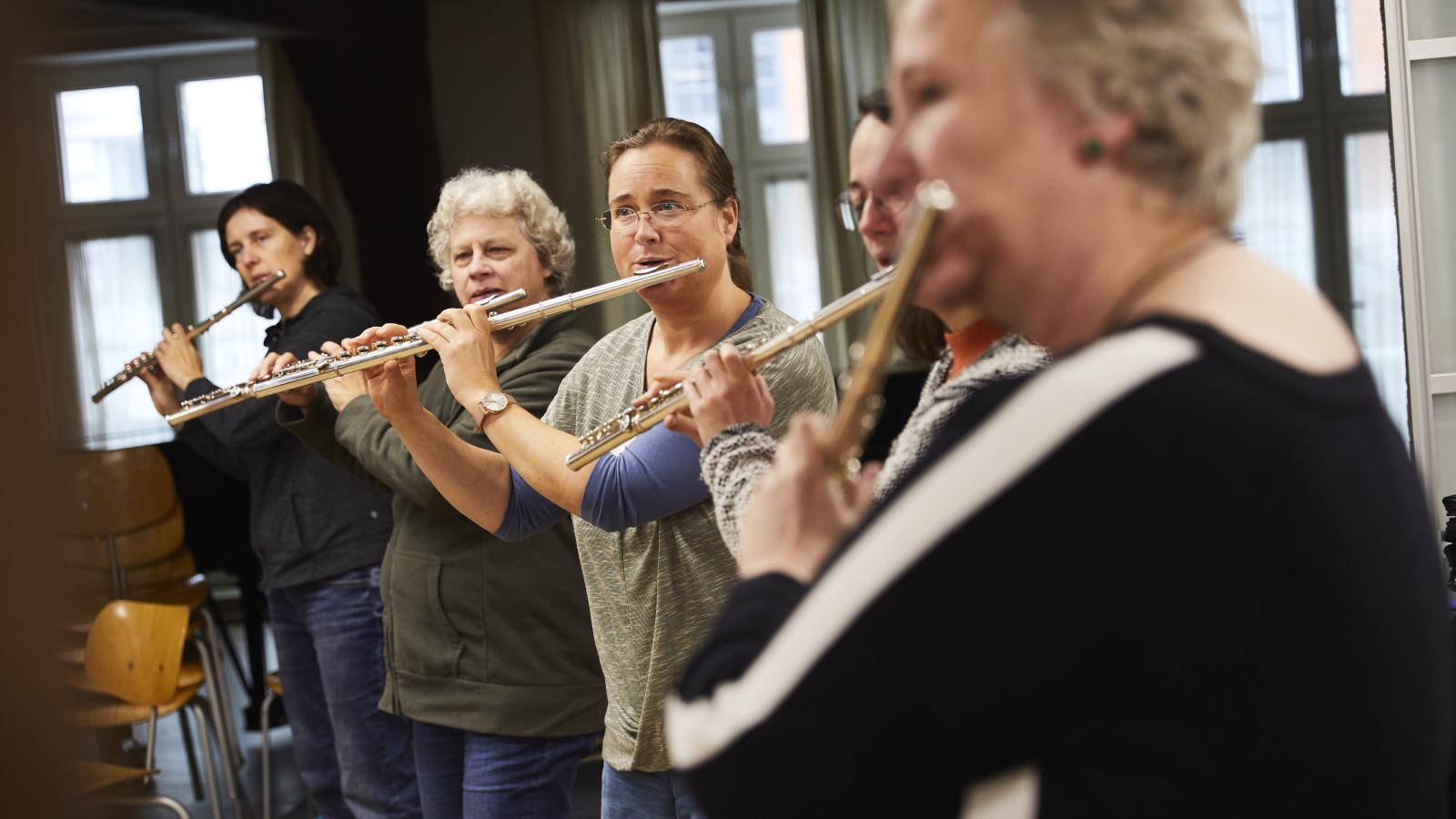 Blick auf eine Gruppe von erwachsenen Lehrkräften, die gemeinsam Querflöte spielen