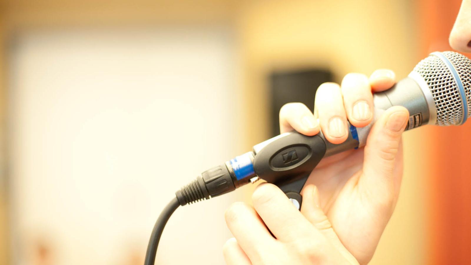 Blick auf ein Mikrofon, dass eine Sänger vor ihren Mund hält