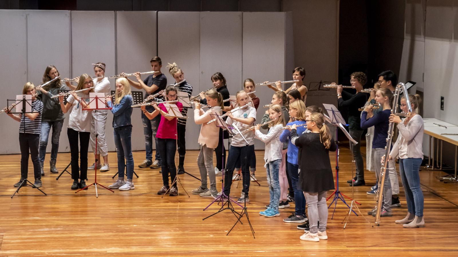 Blick auf ein Querflötenensemble, bestehend aus 21 jungen Schülerinnen und Schülern