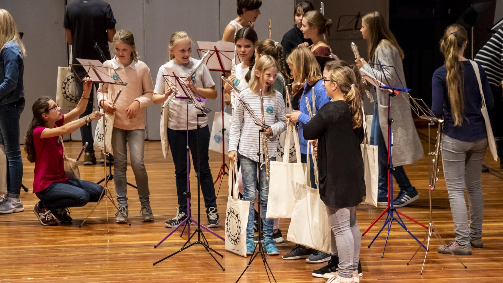 Schülerinnen und Schüler kurz vor einer Flötenensembleprobe auf der Bühne im Großen Saal der MHL
