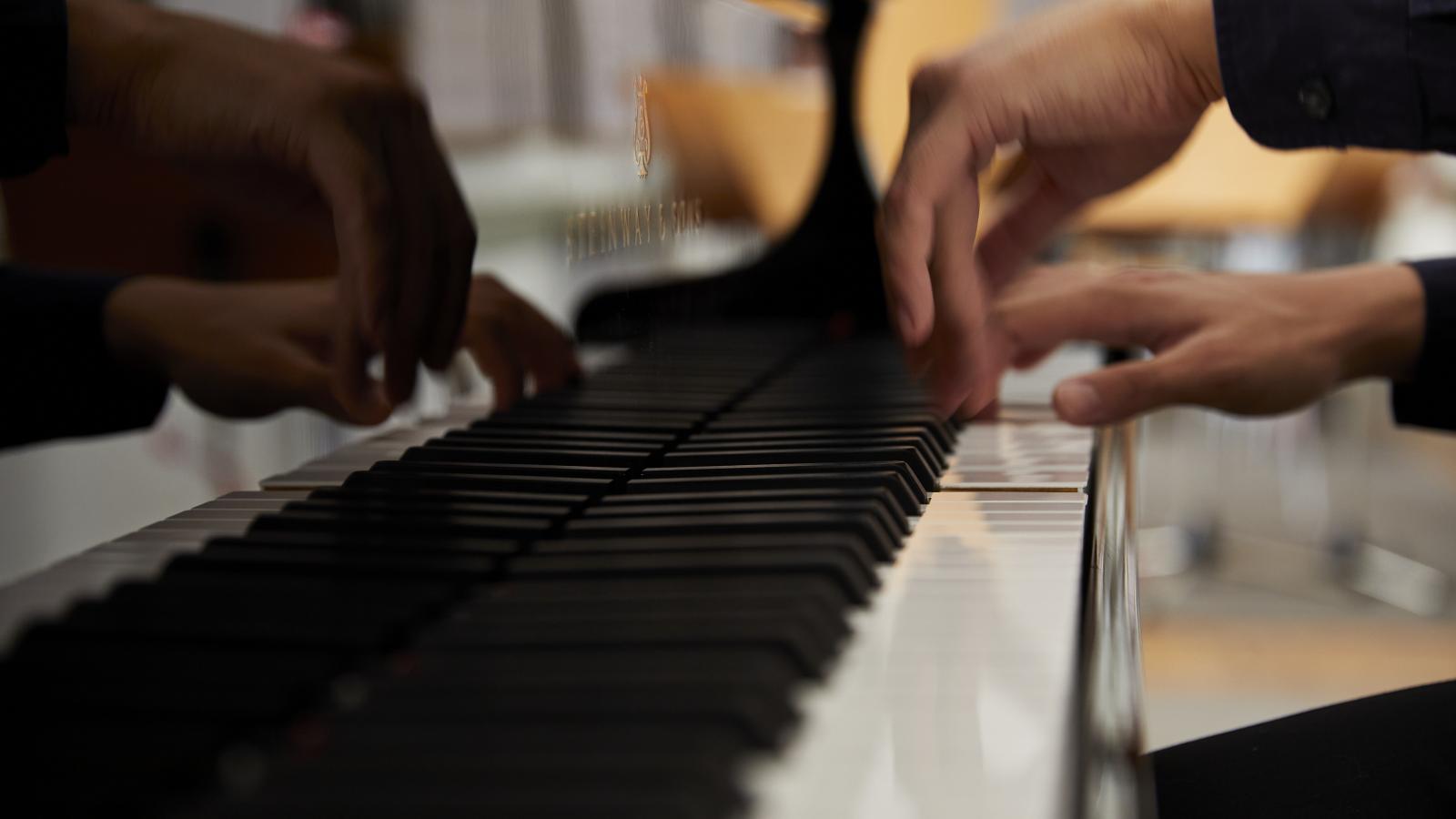 Blick auf die Hände eines Klavierstudenten an einem Flügel