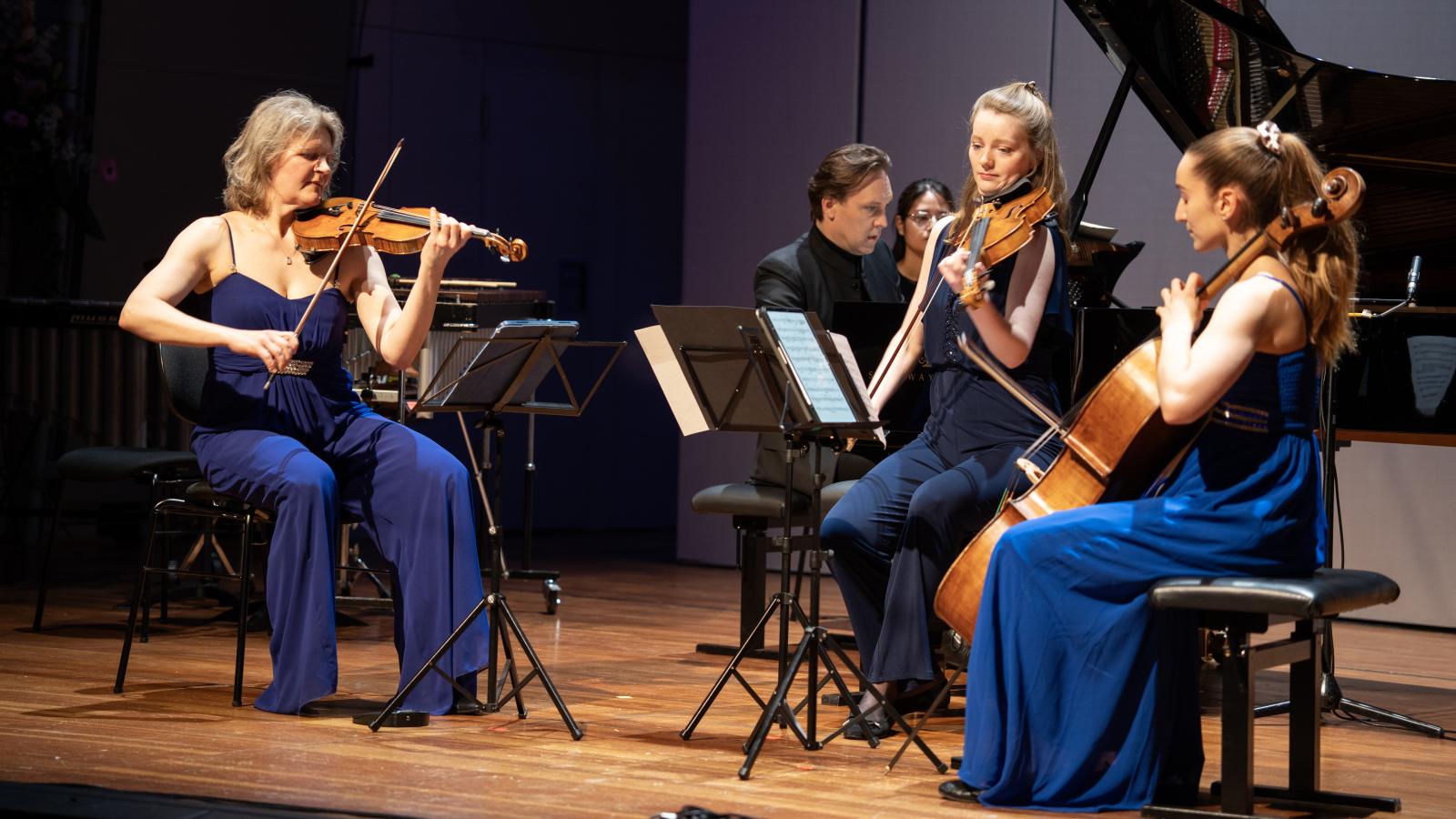 Dozierende und Studierende spielen zusammen ein Klavierquartett auf der Bühne des Großen Saals