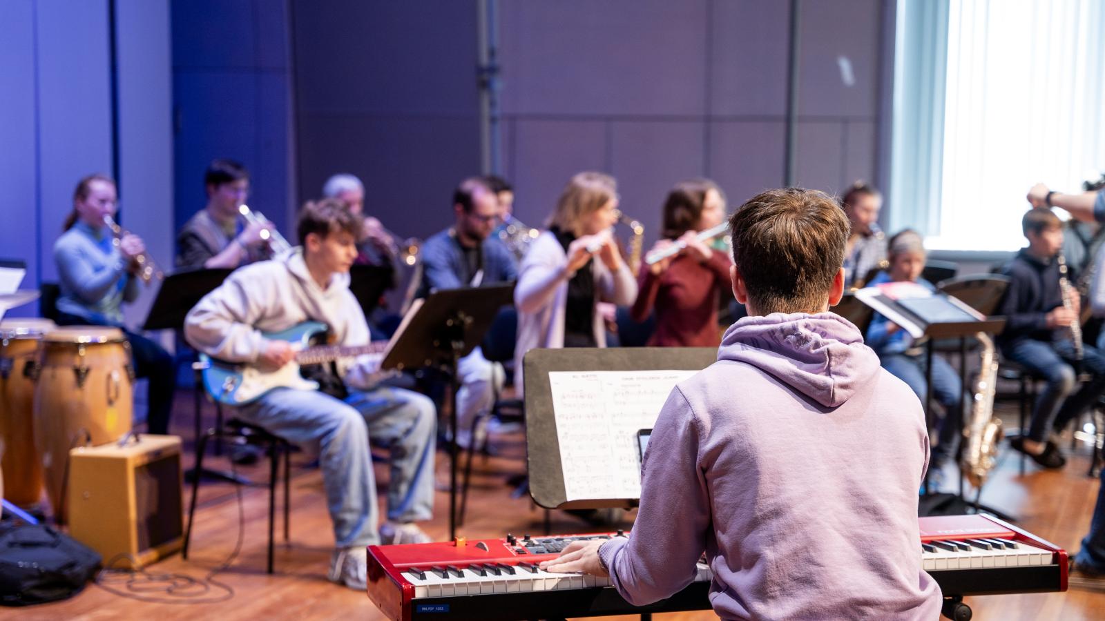Blick auf eine Gruppe Schülerinnen und Schüler, die zusammen Musik machen