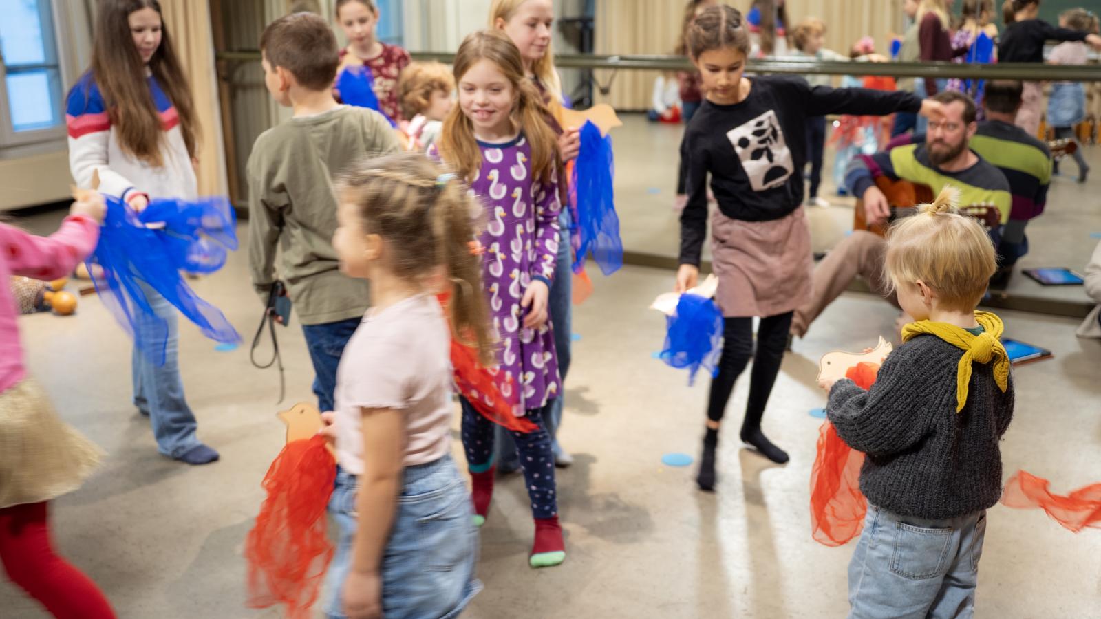 Blick auf eine Gruppe von Schülerinnen und Schülern, die mit sich zur Musik im Raum bewegen.