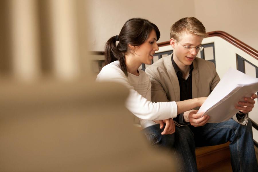 Eine Studentin weist einem Kommilitonen auf eine Besonderheit in einer Broschüre