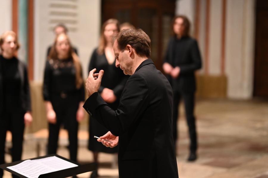 Blick von der Seite auf Chorleitungsprofessor Johannes Knecht, der den MHL-Kammerchor in einer Kirche dirigiert