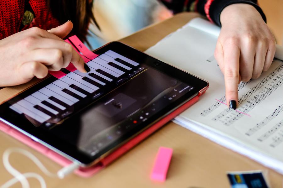 Eine Lehrerin zeigt einer Schülerin, welche Note sie auf einer digitalen Klaviertastatur anschlagen soll.   
