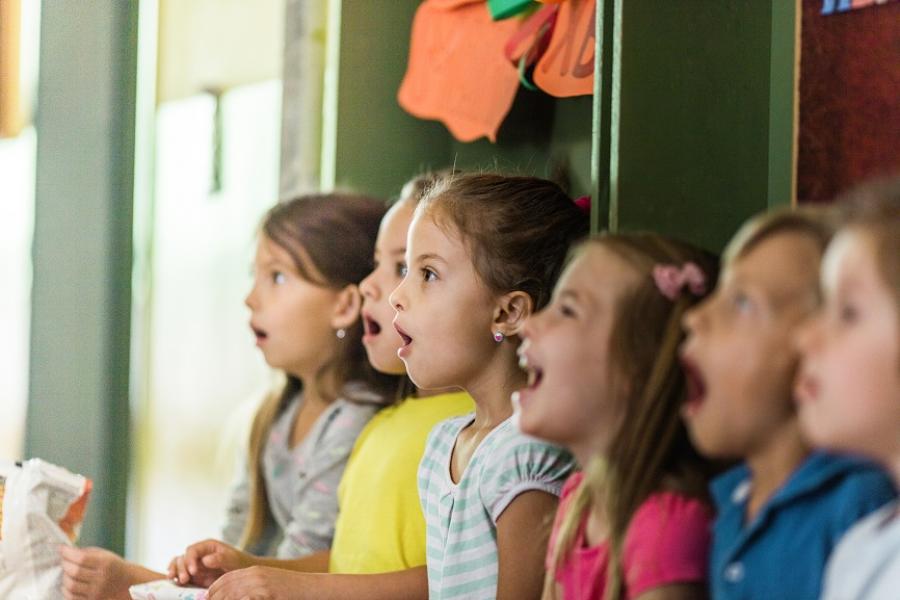 Blick auf eine kleine Gruppe von Kindern im Grundschulalter, die im Musikraum vor einer Tafel singen.