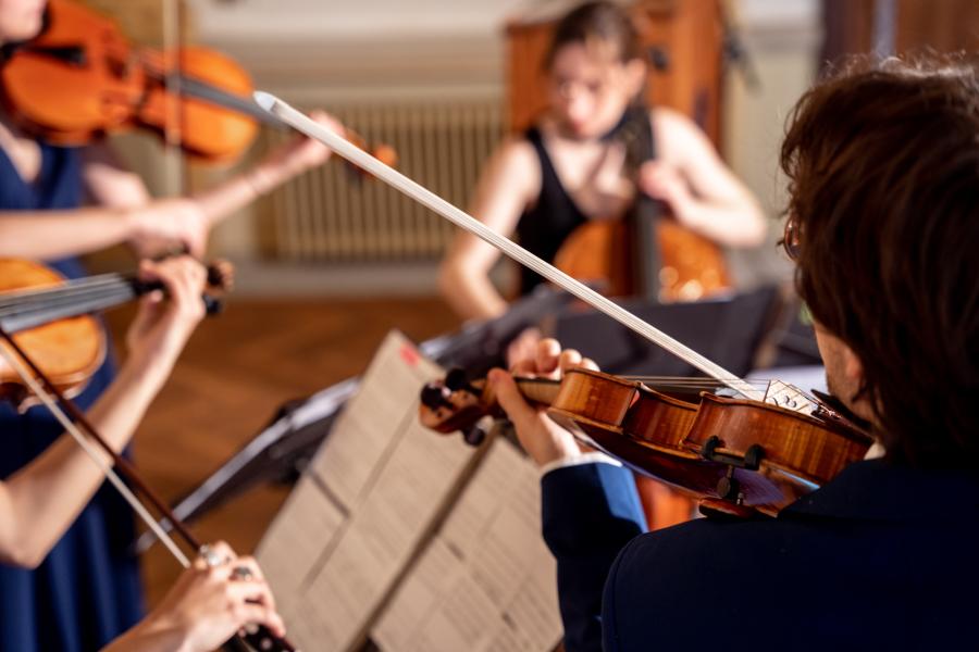 Blick auf vier Studierende, die zusammen ein Sreichquartett spielen