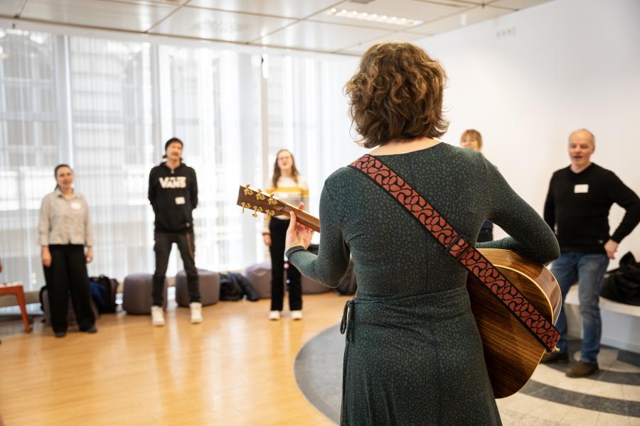 Blick auf eine Gruppe Erwachsene, die an der Gitarre begleitet zusammen singen