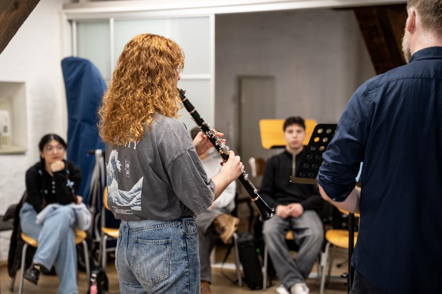 Eine Studieninteressierte spielt einem Klarinettenprofessor ein Stück vor.