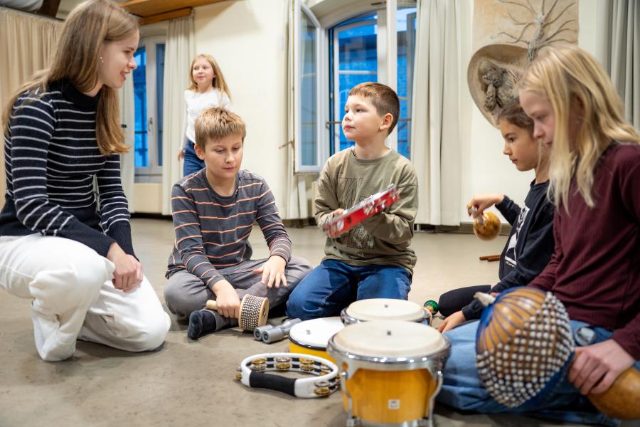 Eine Oberstufenschülerin macht Musik mit Kindern im Grundschulalter