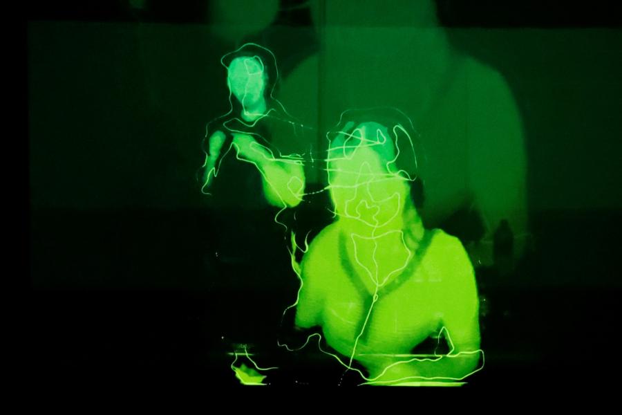 Verzerrter Blick auf zwei Musizierende in grüner, schemenhafter Darstellung auf schwarzem Hintergrund