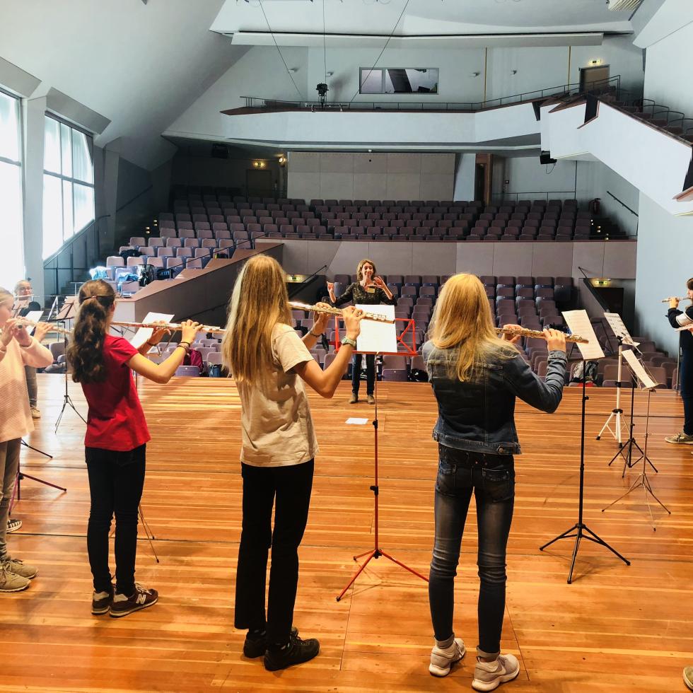 Blick auf eine Gruppe von musizierenden Querflötenspieler von der Bühne des Großen Saals der MHL in den Zuschauerraum