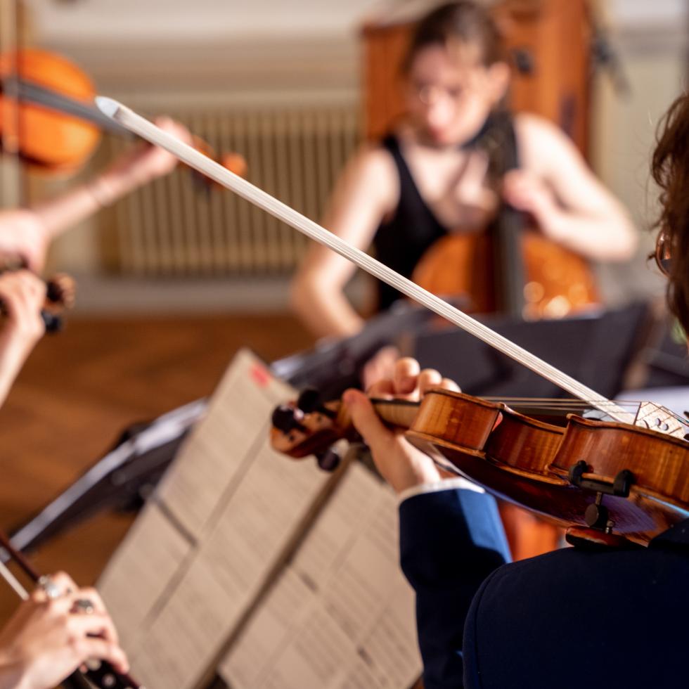 Blick auf vier Studierende, die zusammen ein Sreichquartett spielen