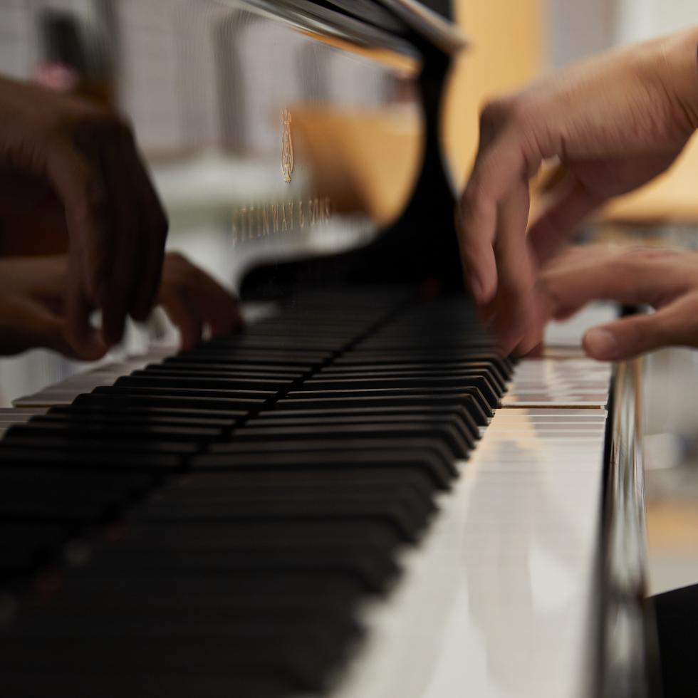 Blick auf die Hände eines Klavierstudenten an einem Flügel