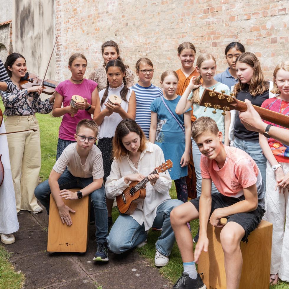 Blick auf eine Gruppe von Schülerinnen und Schülern, die zusammen Musik machen