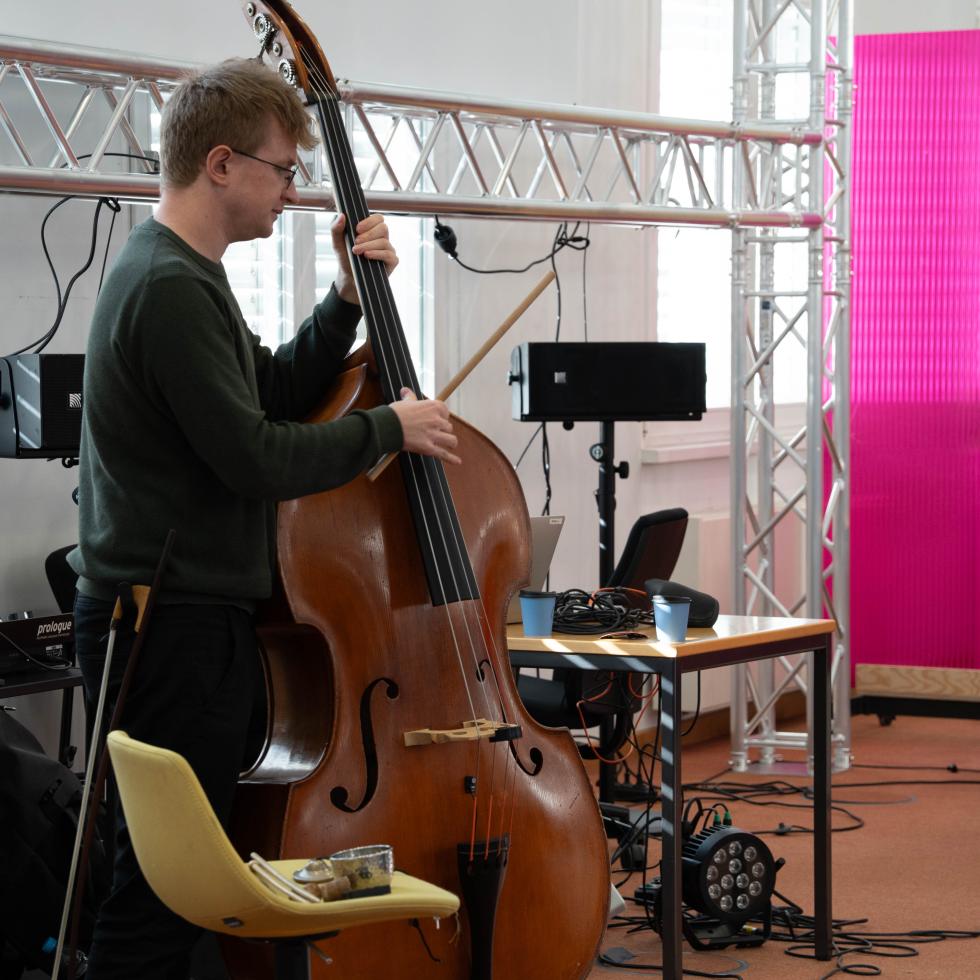 Blick auf einen Kontrabassisten, der mit Hilfe technischer Unterstützung im ehemaligen Bundesbankgebäude improvisiert