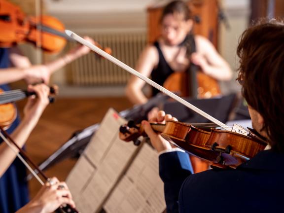 Blick auf vier Studierende, die zusammen ein Sreichquartett spielen