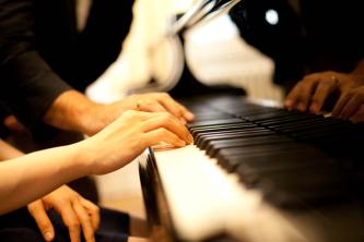 Blick auf Hände, die auf einer Klaviertastatur spielen