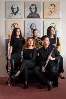 Quantum Quintet vor Brahms Gemälden. Schauen alle nach rechts mit Instrumenten in der Hand